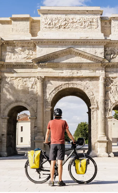 Cycliste devant l'Arc de Triomphe à Orange  © Un monde à vélo